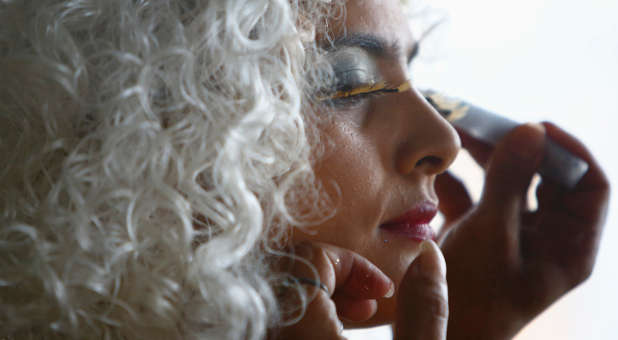 A transgender applies makeup before participating in an LGBT pride parade. Two U.S. companies were sued last week as the government filed its first-ever federal lawsuits for transgender discrimination.