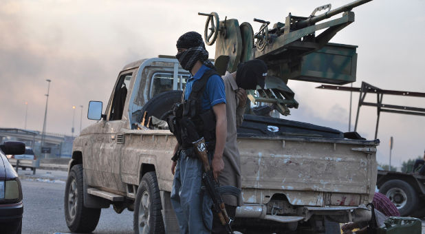 Fighters of the Islamic State of Iraq and the Levant (ISIS) stand guard at a checkpoint in the northern Iraq city of Mosul.