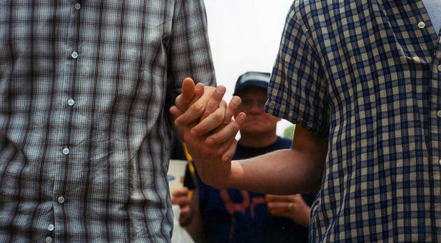 A gay couple holds hands.