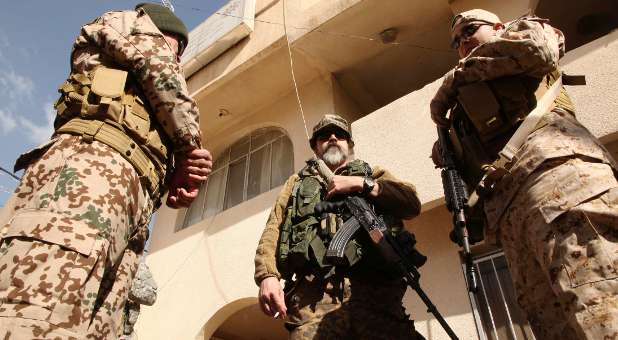 Scott, (C) a Westerner who has joined the Iraqi Christian militia Dwekh Nawsha to fight against Islamic State militants, carries his weapon at the office of the Assyrian political party in Dohuk.