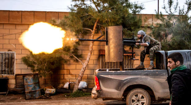 A fighter of the Kurdish People's Protection Units (YPG) fires an anti-aircraft weapon from Tel Tawil village in the direction of Islamic State fighters.