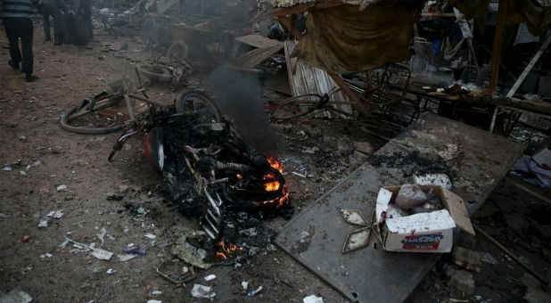 People inspect a site hit by missiles fired by Syrian government forces on a busy marketplace in the Douma neighborhood of Damascus