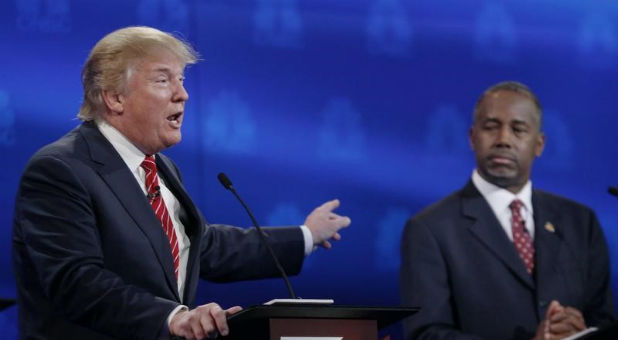 Republican U.S. presidential candidate businessman Donald Trump speaks as Dr. Ben Carson (R) looks on at the 2016 U.S. Republican presidential candidates debate held by CNBC.