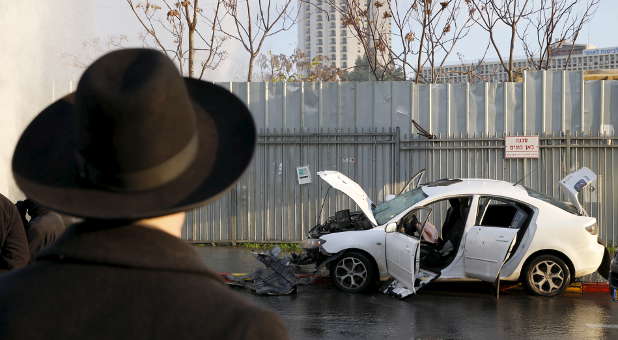 An Israeli man stands next to the scene where a motorist rammed into a bus stop, injuring at least nine people before he was shot dead in Jerusalem, according to Israeli police Dec. 14, 2015.