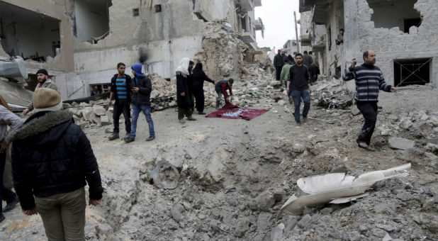 Residents inspect a crater at a site hit by what activists said were three consecutive air strikes carried out by the Russian air force in the rebel-controlled area of Maaret al-Numan town in Idlib province, Syria