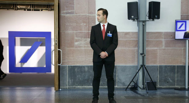 A security officer stands at the entrance as Deutsche Bank CEO Cryan is seen on a video screen while addressing the bank's annual general meeting in Frankfurt