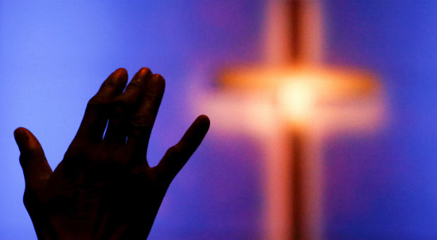 A woman raises her hand during a prayer service at the Concord Baptist Church, one day after a lone gunman ambushed and killed five police officers at a protest decrying police shootings of black men, in Dallas.