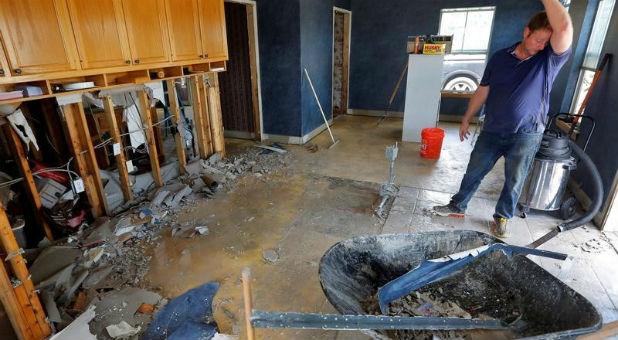 Steve Bogan wipes sweat off his forehead as he cleans out flooding at his family's business in Denham Springs, Louisiana