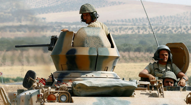 Turkish soldiers on an armoured personnel carrier escort a military convoy on a main road in Karkamis on the Turkish-Syrian border in the southeastern Gaziantep province, Turkey