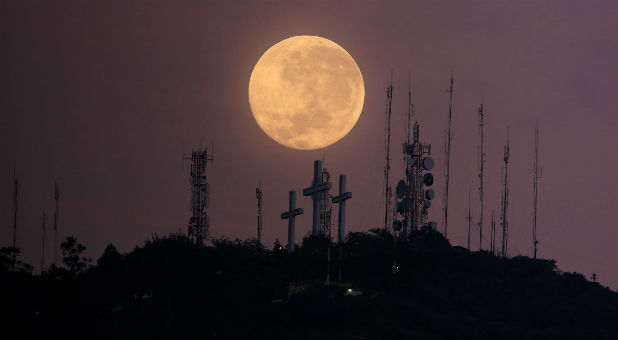 The full moon is seen above the hill of the three crosses in Cali, Colombia