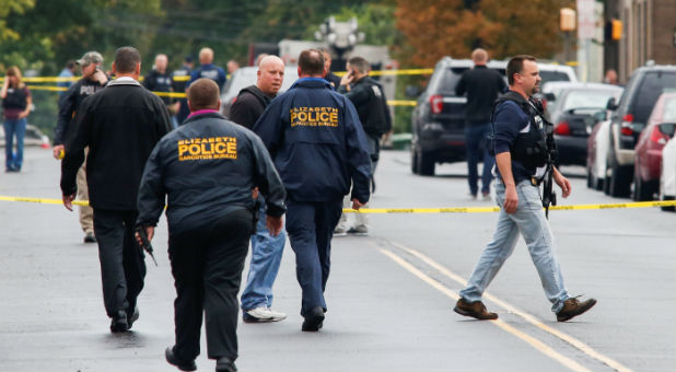 Police officers walk near the site where Ahmad Khan Rahami, sought in connection with a bombing in New York, was taken into custody