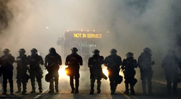 Police officers wearing riot gear block a road during protests after police fatally shot a man in the parking lot of an apartment complex in Charlotte