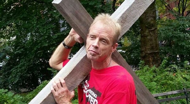 Robert Boatwright carries his cross by the Temple of Baal arch.