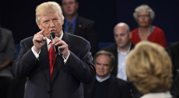 Republican U.S. presidential nominee Donald Trump speaks as Democratic U.S. presidential nominee Hillary Clinton (R) listens during their presidential town hall debate