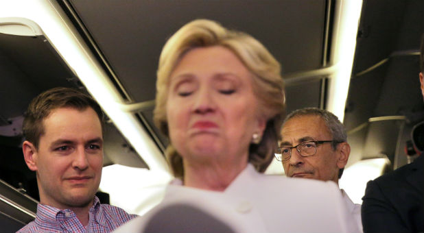 John Podesta (R), chairman of U.S. Democrat Hillary Clinton's presidential campaign, listens as she talks to the media inside of her campaign plane after the third and final 2016 presidential campaign debate in North Las Vegas, Nevada