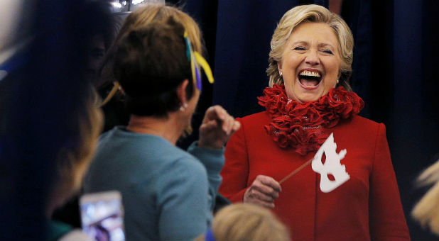 U.S. Democratic presidential nominee Hillary Clinton holds a Halloween mask while joking with her staff on her campaign plane