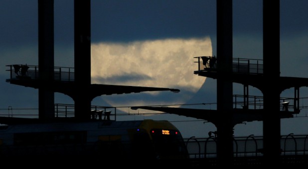 A commuter train en route to the suburb of Hornsby crosses on the Sydney Harbor Bridge under the Super Moon