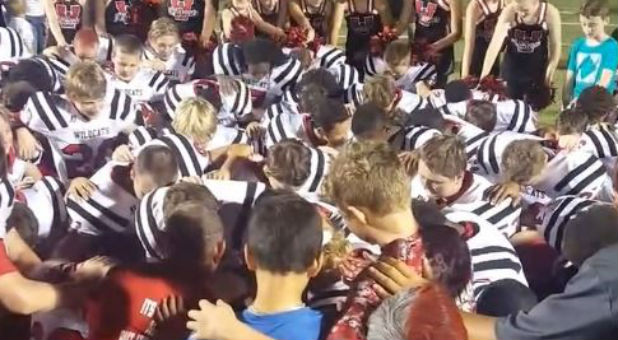 Eddie Metcalf is lost in the crowd as he prays with students.