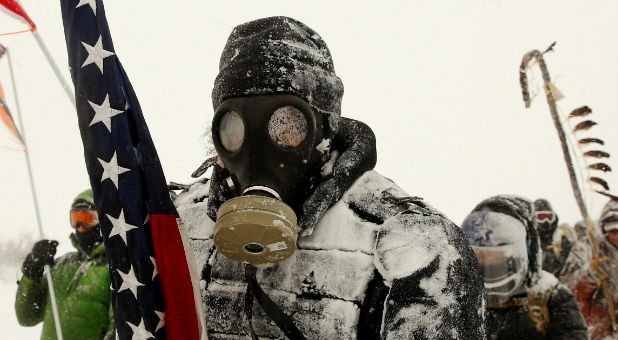 A man takes part in a march with veterans to Backwater Bridge just outside of the Oceti Sakowin camp during a snow fall as