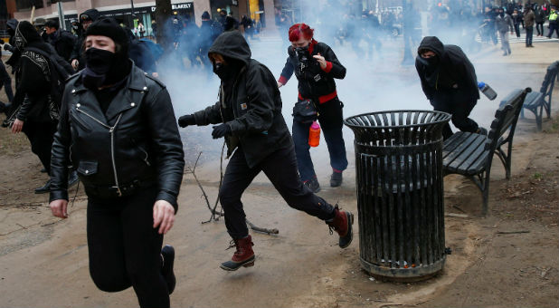 Activists race after being hit by a stun grenade while protesting against U.S. President-elect Donald Trump on the sidelines of the inauguration in Washington