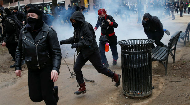 Activists race after being hit by a stun grenade while protesting against U.S. President-elect Donald Trump on the sidelines of the inauguration in Washington.