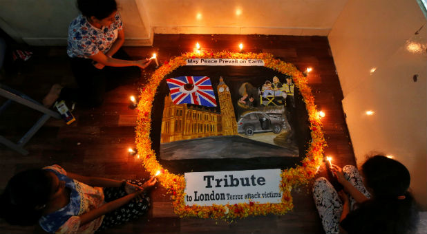 Girls light candles on a painting dedicated to the victims of the recent London attack