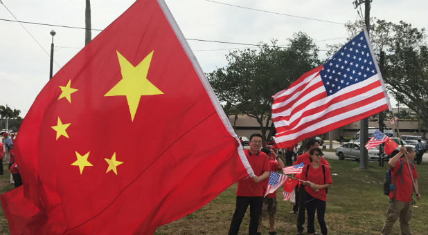 A group that identified itself as China-U.S. Enterprise waits to view the motorcade of Chinese President Xi Jinping before his meeting with U.S. President Donald Trump