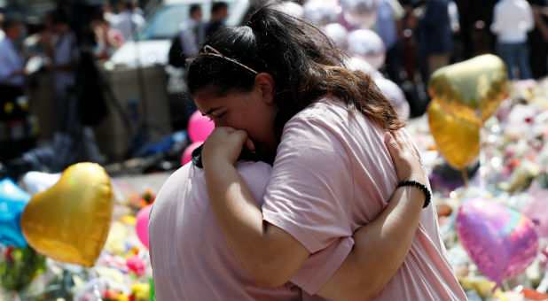 Crowds look at the balloons, flowers and messages of condolence left for the victims of the Manchester Arena attack, in central Manchester, Britain