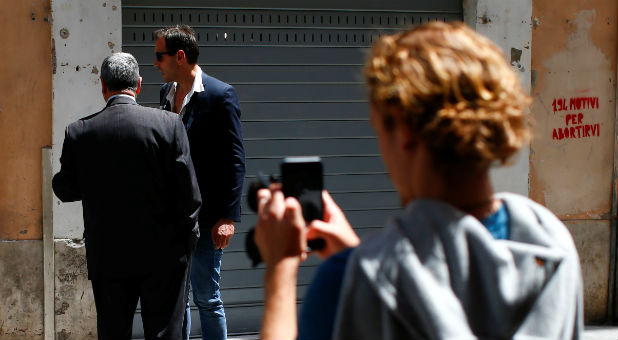 People look at a mural signed by