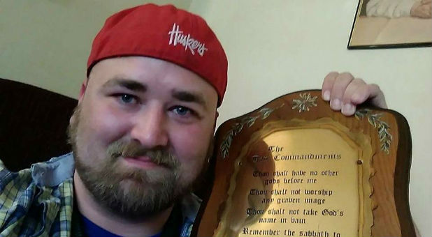 Michael Tate Reed holds up a Ten Commandments plaque.