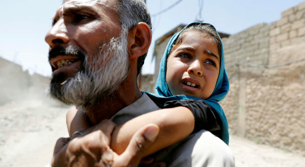 A man carries his daughter on his back after fleeing their home due to fighting between the Iraqi forces and Islamic State militants in Mosul's al-Zanjili's district in Iraq.