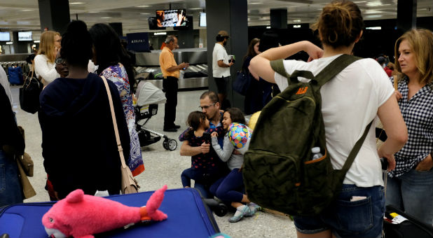 Ahmed Khalil, an Egyptian national residing in the United States, hugs and kisses his daughters Laila, 6, left, and Farida, 8, right, as they arrive at Washington Dulles International Airport in the hour after the Trump administration's travel ban was allowed back into effect pending further judicial review.