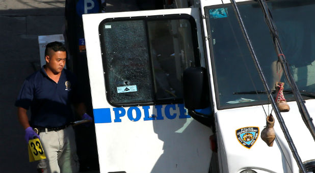 A New York City Police Department (NYPD) investigator carries an evidence marker to a police vehicle where a gunman fatally shot a female New York City police officer in an unprovoked attack early on Wednesday in the city's Bronx borough, New York.