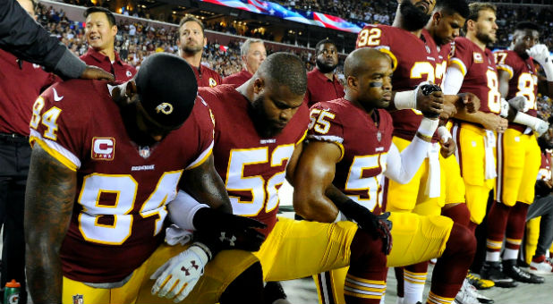 Washington Redskins tight end Niles Paul, linebacker Ryan Anderson and linebacker Chris Carter kneel with teammates.