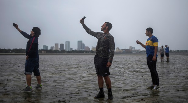 Residents stand in an empty Tampa Bay.