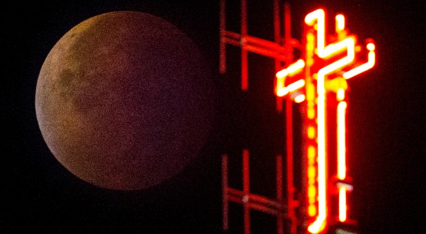 The cross of the Koekelberg Basilica is seen while the moon turns orange during a total