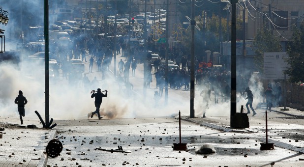 Palestinian protesters run for cover from tear gas fired by Israeli troops during clashes at a protest against U.S. President Donald Trump's decision to recognize Jerusalem as the capital of Israel.