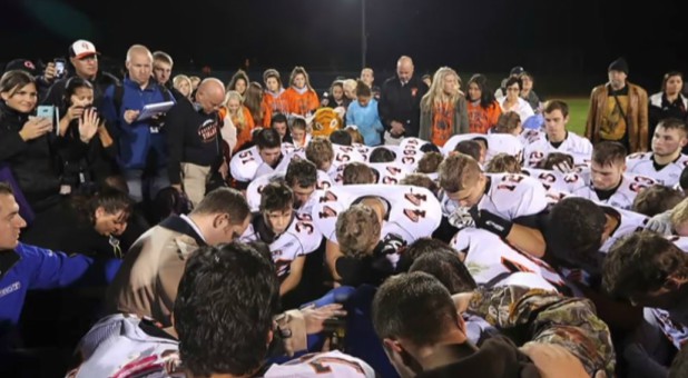 Kennedy's team prays on the field.