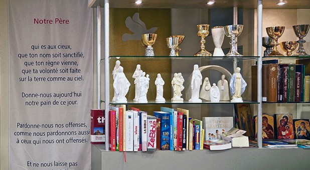 A banner with the new French translation of the Lord’s Prayer, at left, for churches that want to help parishioners recite it aloud during Mass, on sale in a religious goods shop in Paris on Jan. 30, 2018.