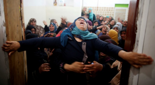 Mourners hold back a relative of Palestinian Hamdan Abu Amshah, who was killed along Israel border with Gaza, during his funeral in Beit Hanoun town, in the northern Gaza Strip.