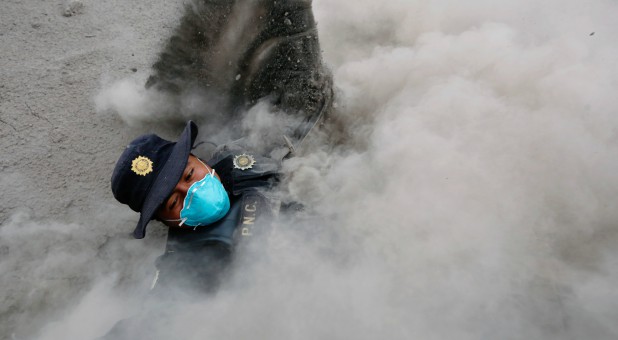 A police officer stumbles while running away from a new pyroclastic flow spewed by the Fuego volcano in the community of San Miguel Los Lotes in Escuintla, Guatemala.