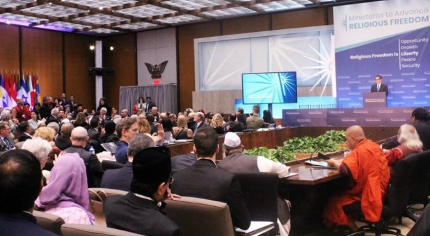 Survivors of religious persecution, left, stood and were recognized by Sam Brownback, at podium on right, U.S. ambassador-at-large for international religious freedom, during the start of the Ministerial to Advance Religious Freedom at the State Department on July 24, 2018.