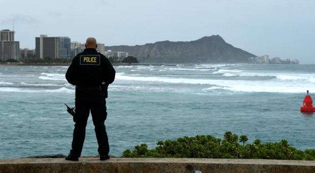 Honolulu police officer Chad Asuncion monitors the water conditions and warns surfers about the conditions as Hurricane Lane approaches Honolulu, Hawaii.