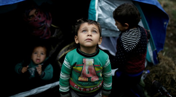 A Syrian refugee boy stands in front of his family tent at a makeshift camp for refugees and migrants next to the Moria camp on the island of Lesbos, Greece.