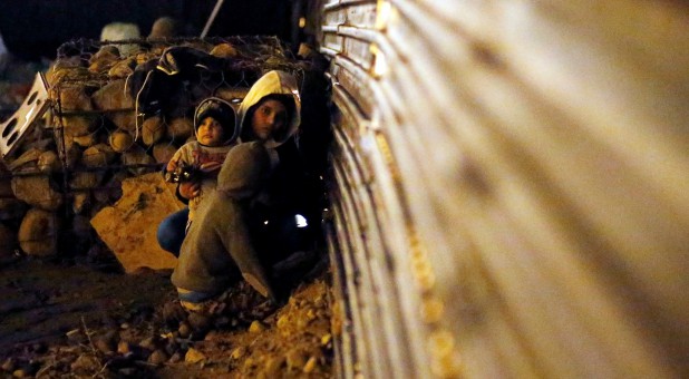 Migrants from Honduras, part of a caravan of thousands from Central America trying to reach the United States, sit near the border fence to cross it illegally from Mexico into the U.S.