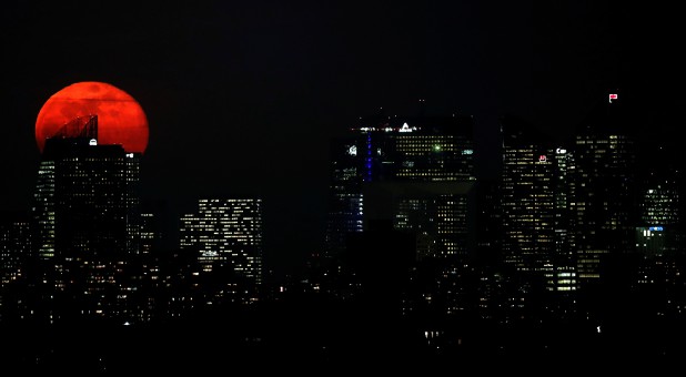 The moon rises behind buildings of the Grande Arche, the headquarters of Areva, Societe Generale and EDF at the financial district of La Defense near Paris, France.