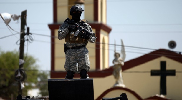 A soldier stands guard after a blockade set by members of the Santa Rosa de Lima Cartel to repel security forces during an anti-fuel theft operation.