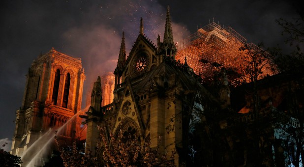 Sparks fill the air as Paris Fire brigade members spray water to extinguish flames as the Notre Dame Cathedral burns in Paris, France.