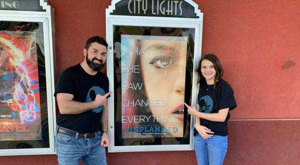 Doug and Grace Johnson stand by a poster for