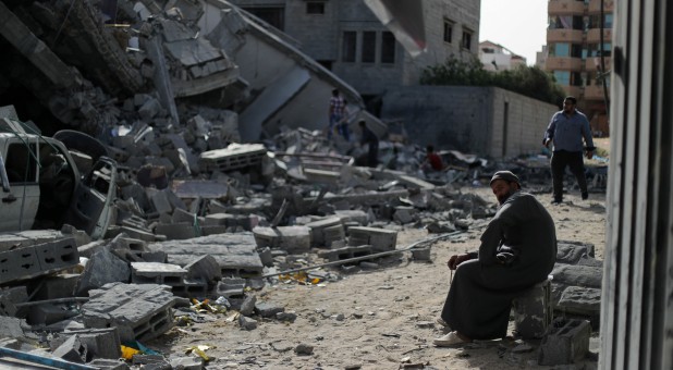 A man sits on debris near a building that was destroyed by Israeli air strikes, in Gaza City.